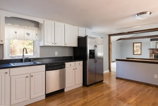 a kitchen with granite countertop white cabinets white appliances and sink
