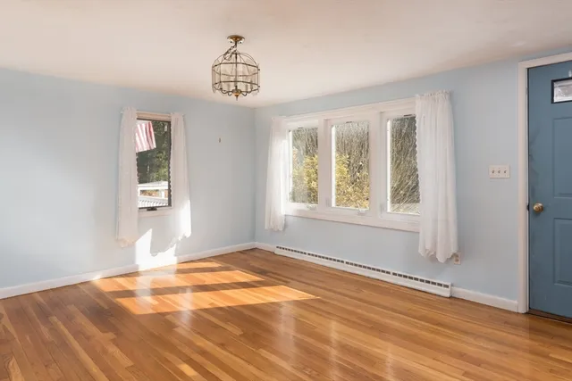 a view of an empty room with window and wooden floor