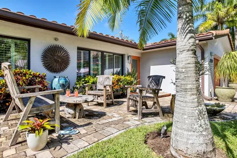 a view of a patio with table and chairs potted plants and a palm tree