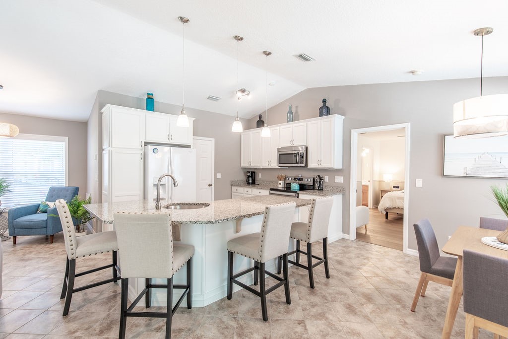 3673 2nd Place Southwest Vero Beach, FL 32968 - Photo 11 of 33 a kitchen with stainless steel appliances a white table chairs and a refrigerator