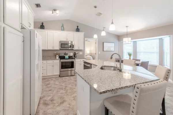 a large kitchen with granite countertop lots of counter top space and refrigerator