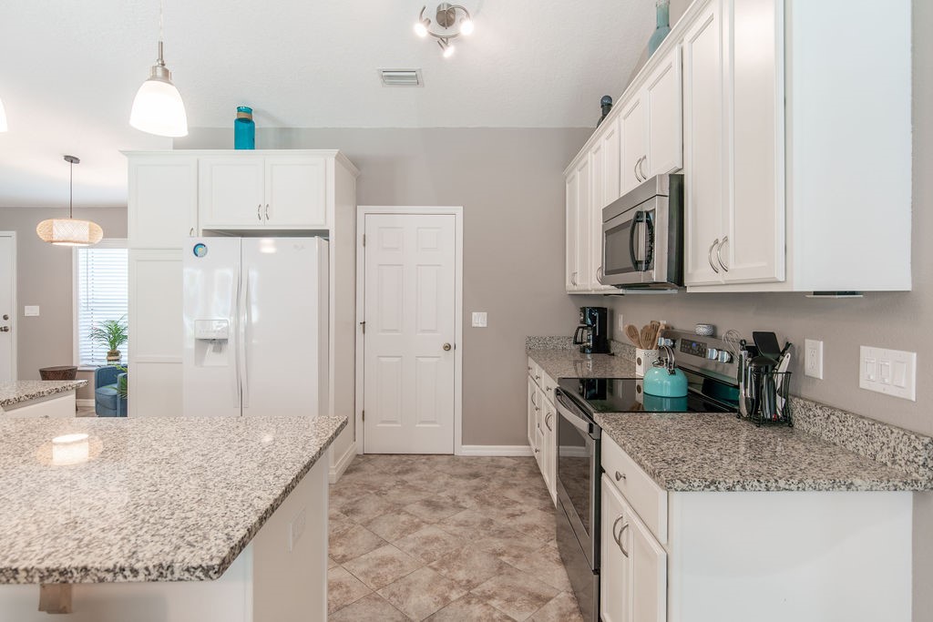 3673 2nd Place Southwest Vero Beach, FL 32968 - Photo 26 of 33 a kitchen with stainless steel appliances granite countertop a sink stove and refrigerator