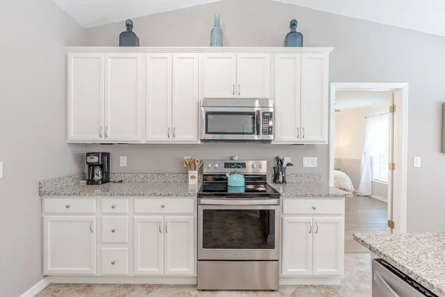 a kitchen with granite countertop white cabinets and stainless steel appliances