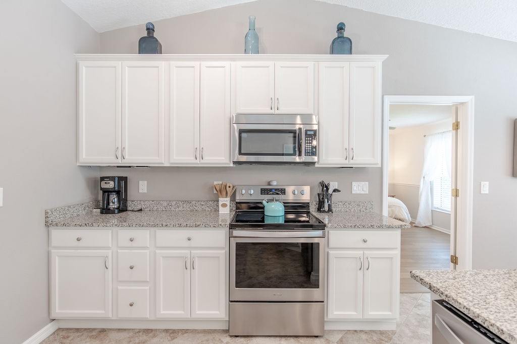 3673 2nd Place Southwest Vero Beach, FL 32968 - Photo 27 of 33 a kitchen with granite countertop white cabinets and stainless steel appliances