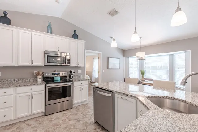 a kitchen with granite countertop a sink stainless steel appliances and white cabinets