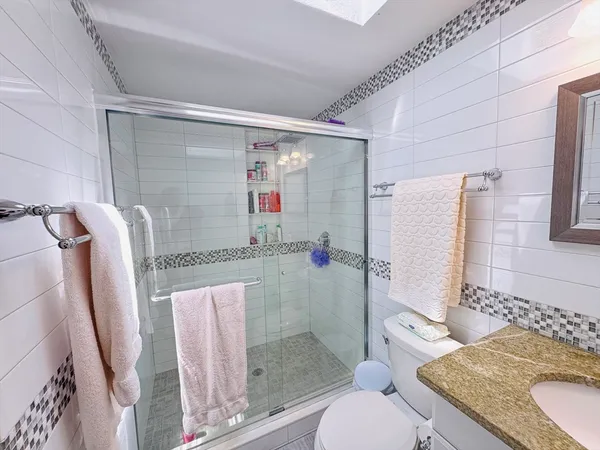 a bathroom with a granite countertop tub sink and toilet