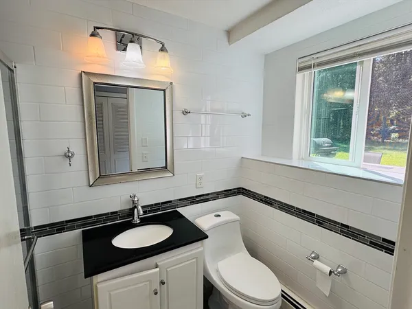 a bathroom with a granite countertop sink vanity mirror and toilet