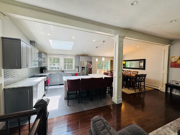 a living room with fireplace furniture and a dining table with wooden floor