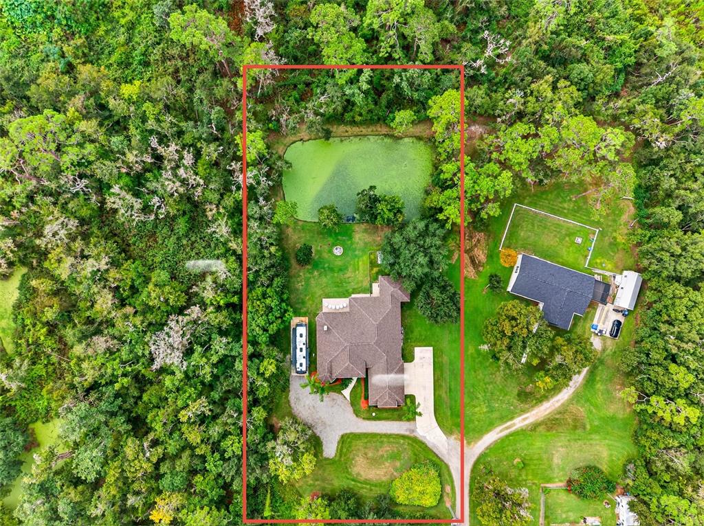 an aerial view of residential house with outdoor space and trees all around