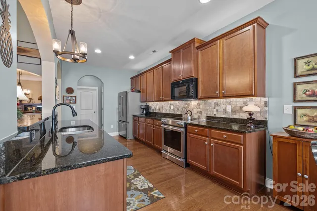 a kitchen with kitchen island granite countertop a sink cabinets and stainless steel appliances