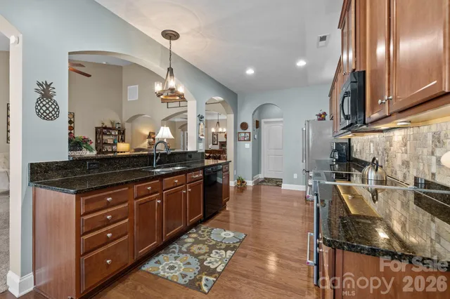 a large kitchen with stainless steel appliances granite countertop a stove and a wooden floors