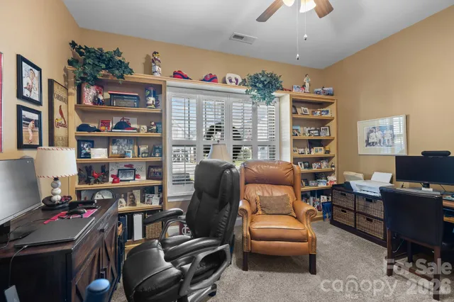 a work room with furniture a bookshelf and a window