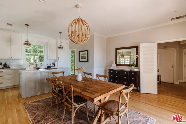 a view of a dining room and livingroom with furniture wooden floor a rug a painting and a chandelier
