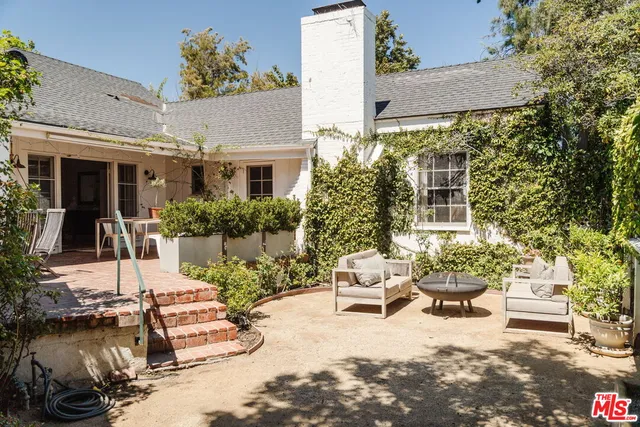 a view of a patio with couches fire pit and a large tree