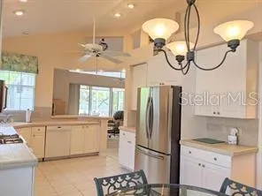 a kitchen with stainless steel appliances granite countertop a refrigerator a sink a stove and white cabinets with wooden floor