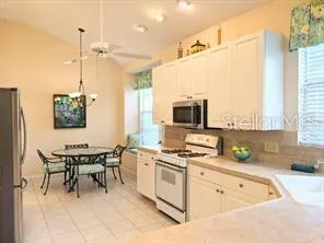 a kitchen with a sink stove and white cabinets with wooden floor