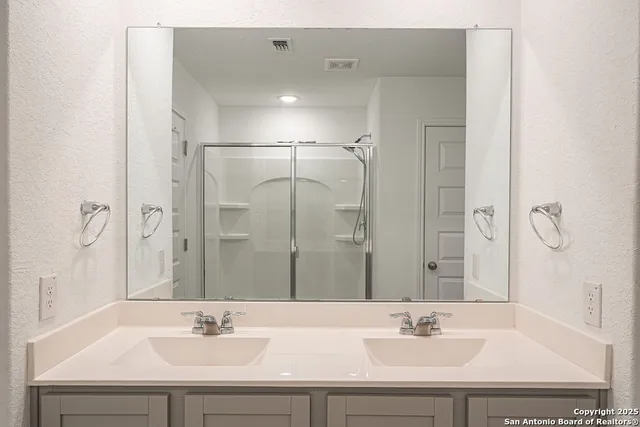 a bathroom with a double vanity sink mirror and shower
