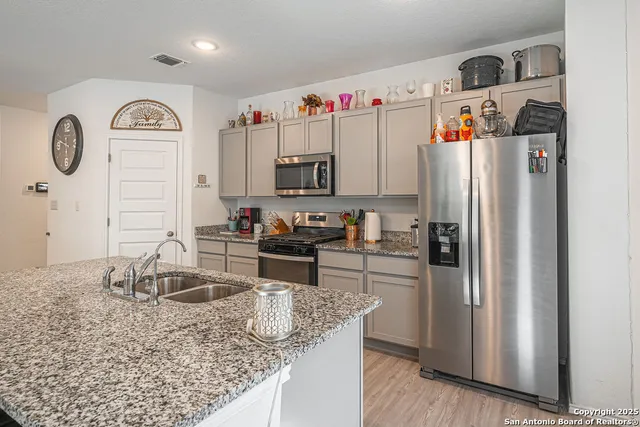 a kitchen with granite countertop a sink stainless steel appliances and white cabinets