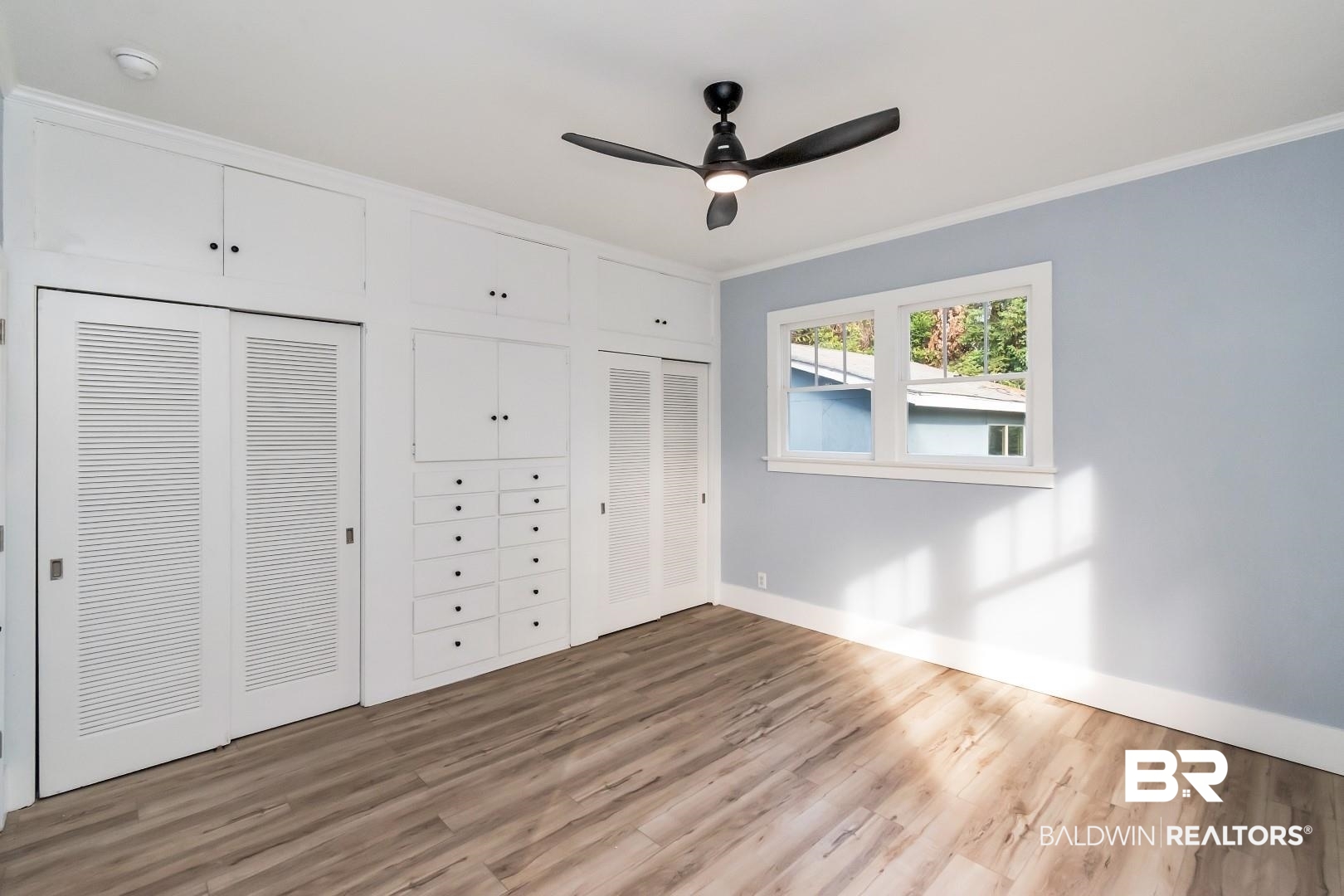 555 Michigan Avenue Mobile, AL 36604 - Photo 18 of 28 Unfurnished bedroom featuring ornamental molding, hardwood / wood-style floors, ceiling fan, and multiple closets
