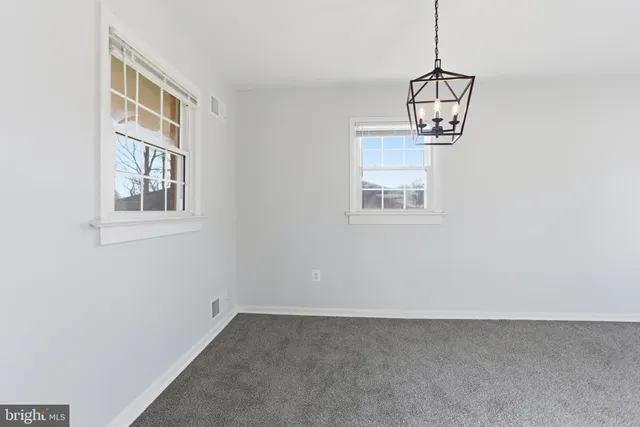 a view of an empty room with window and chandelier fan