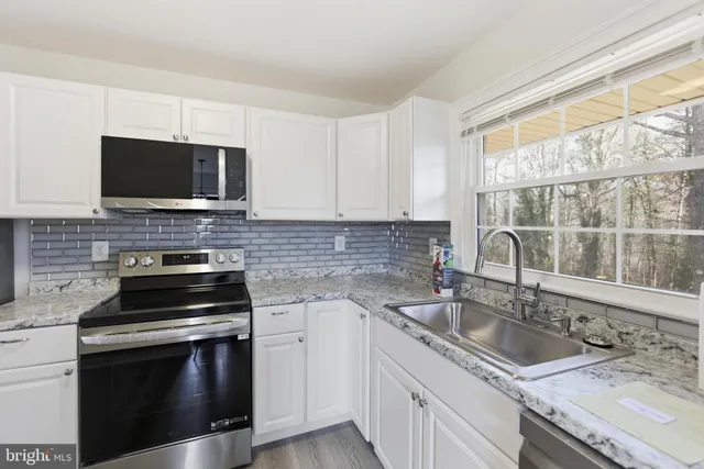 a kitchen with a sink a refrigerator a microwave and cabinets