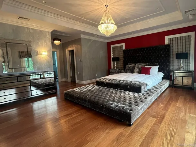 a bedroom with a large bed a flat tv screen and dresser