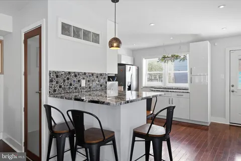 a kitchen with stainless steel appliances granite countertop a dining table chairs and wooden floor