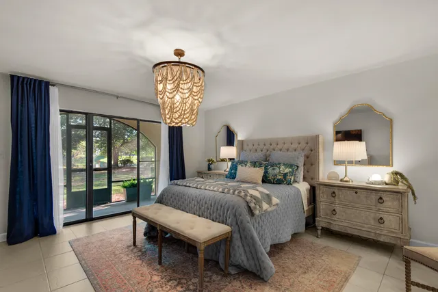 a bedroom with a bed a chandelier and dresser