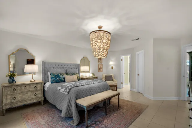 a bedroom with a bed a chandelier and dresser