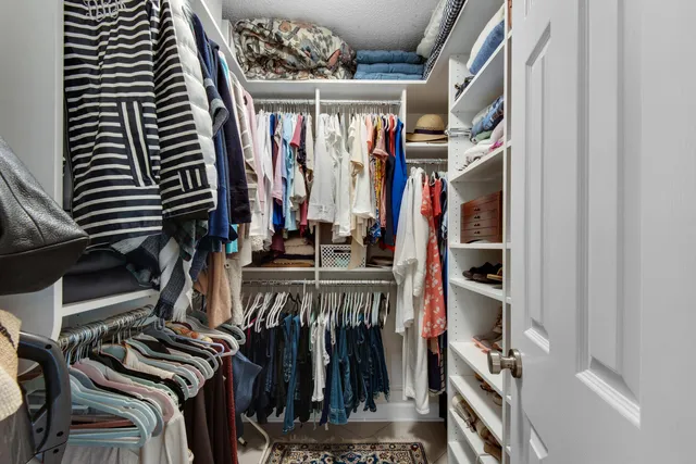 a view of walk in closet with clothes and shoes