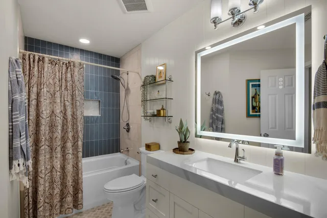 a bathroom with a granite countertop sink a toilet a mirror a vanity and shower