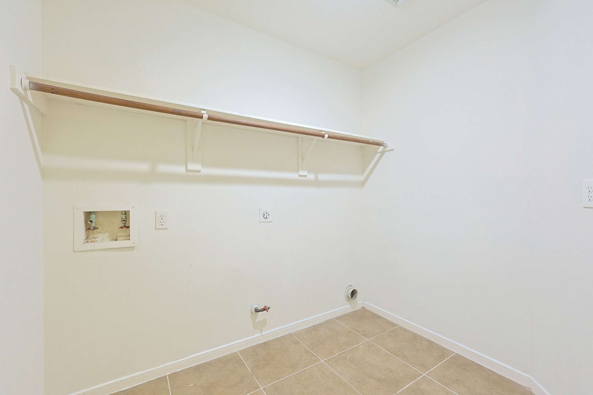23019 Eastgate Village Drive Spring, TX 77373 - Photo 40 of 46 This is a bright, spacious laundry room with tile flooring, hookups for a washer and dryer, and a convenient wall-mounted shelf for storage.