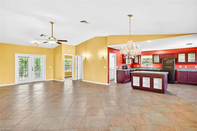 a view of an empty room with window and chandelier fan