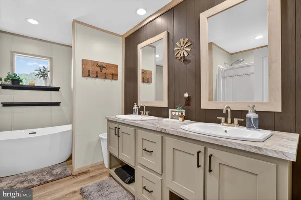 a spacious bathroom with a double vanity sink mirror and bathtub