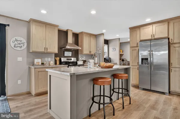 a kitchen with stainless steel appliances granite countertop a refrigerator a stove a sink and a dining table with wooden cabinet