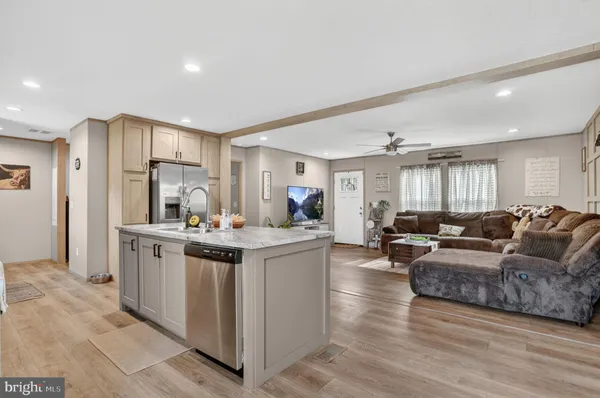 a living room with kitchen island granite countertop wooden floor and white cabinets