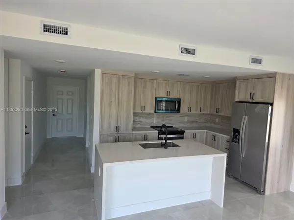 a kitchen with stainless steel appliances a refrigerator a sink a stove top oven a sink and dishwasher