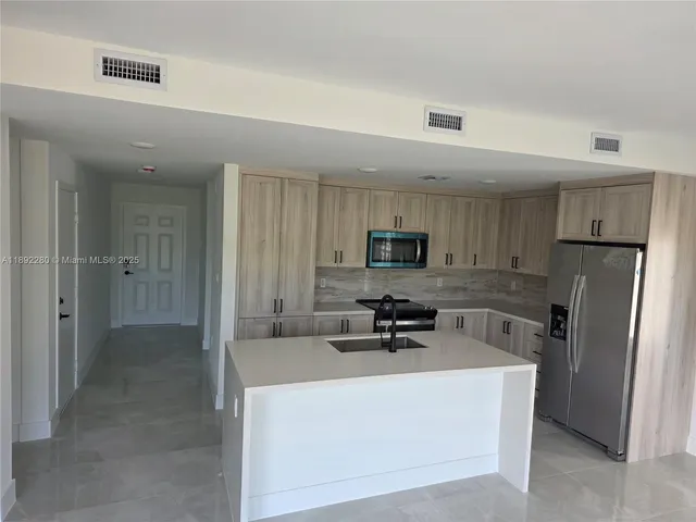 a kitchen with stainless steel appliances a refrigerator a sink a stove top oven a counter space and cabinets