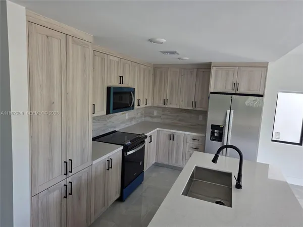 a kitchen with granite countertop a stove a sink dishwasher and a refrigerator