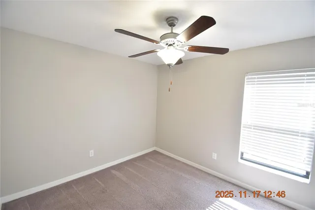 an empty room with windows and fan