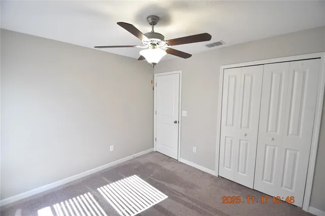 an empty room with a chandelier fan and closet