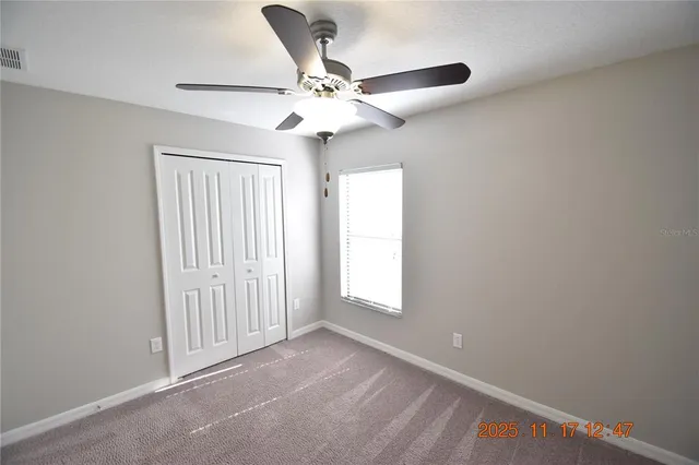 an empty room with a ceiling fan and a window