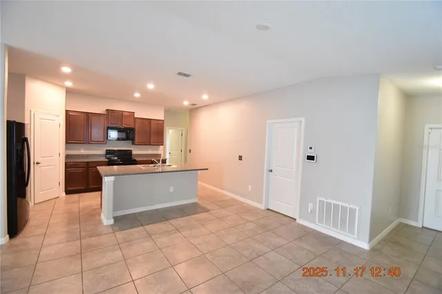 a large kitchen with stainless steel appliances kitchen island granite countertop a large counter top a sink and a refrigerator