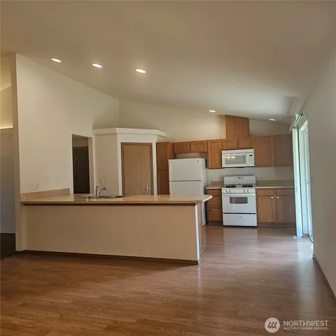 a living room with stainless steel appliances kitchen island granite countertop a stove and a refrigerator
