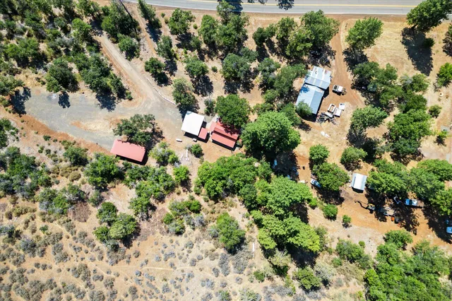 an aerial view of a house with a yard and trees all around