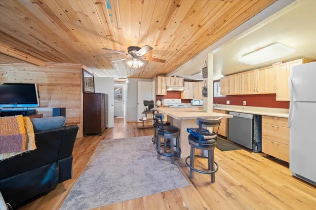 a kitchen with stainless steel appliances a refrigerator a stove top oven and a dining table with wooden floor