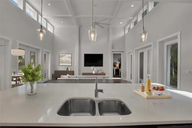 a kitchen with kitchen island a sink stainless steel appliances and living room view