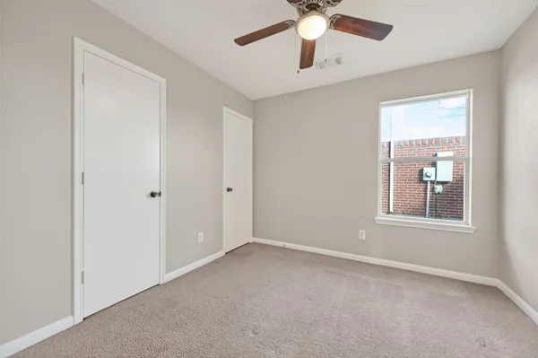 an empty room with chandelier fan and windows