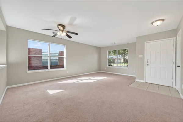 a view of an empty room with window and chandelier fan