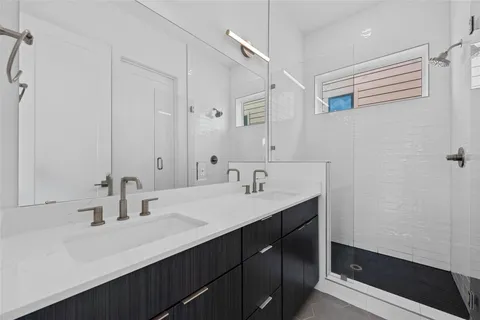 a bathroom with a double vanity sink a mirror and a shower